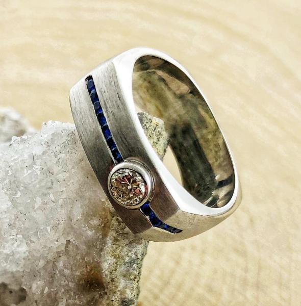 14 karat white gold gentleman's ring with a 0.31ct round brilliant diamond and 12 diamond cut blue sapphires. Designed by Kurt Rose.  $2350.00