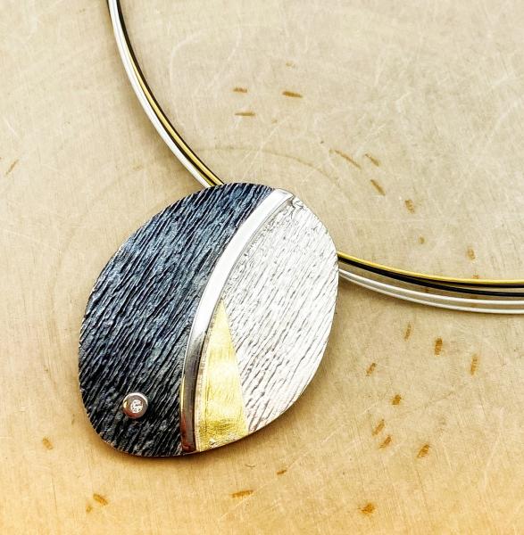 Sterling silver and 18 karat gold oval textured necklace with diamond accent. $350.00