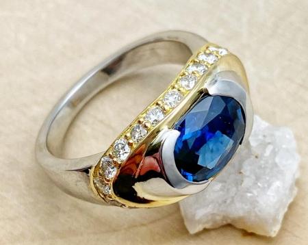 18 karat white and yellow gold ring with a 2.1 carat oval blue sapphire and diamonds totaling 0.76 carat. 117-10621