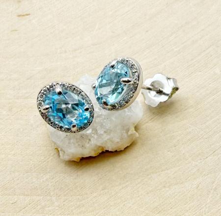 14 karat white gold oval Swiss blue topaz and diamond halo earrings. $1070.00